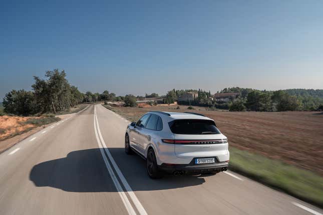 Une Porsche Cayenne S E-Hybrid 2024 blanche s'éloigne de la caméra sur une autoroute espagnole